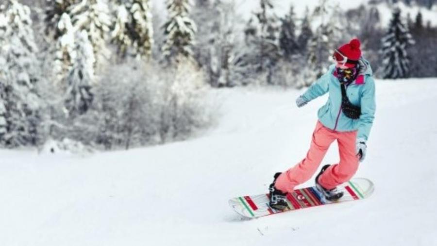 kobieta-w-kombinezon-narciarski-wyglada-na-jej-ramieniu-schodzac-ze-wzgorza-na-jej-snowboard_8353-10